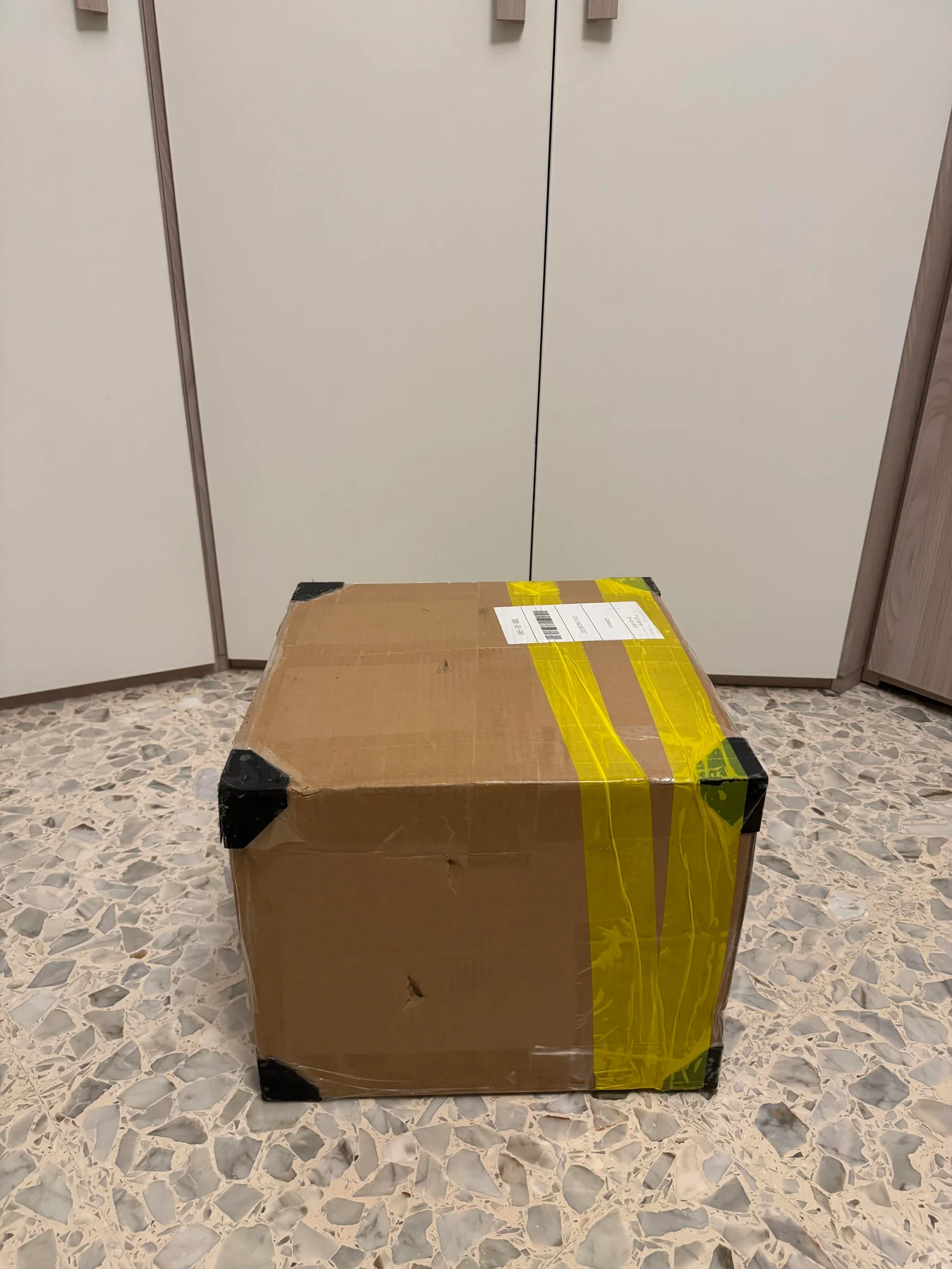 Sealed cardboard parcel with yellow packing tape.