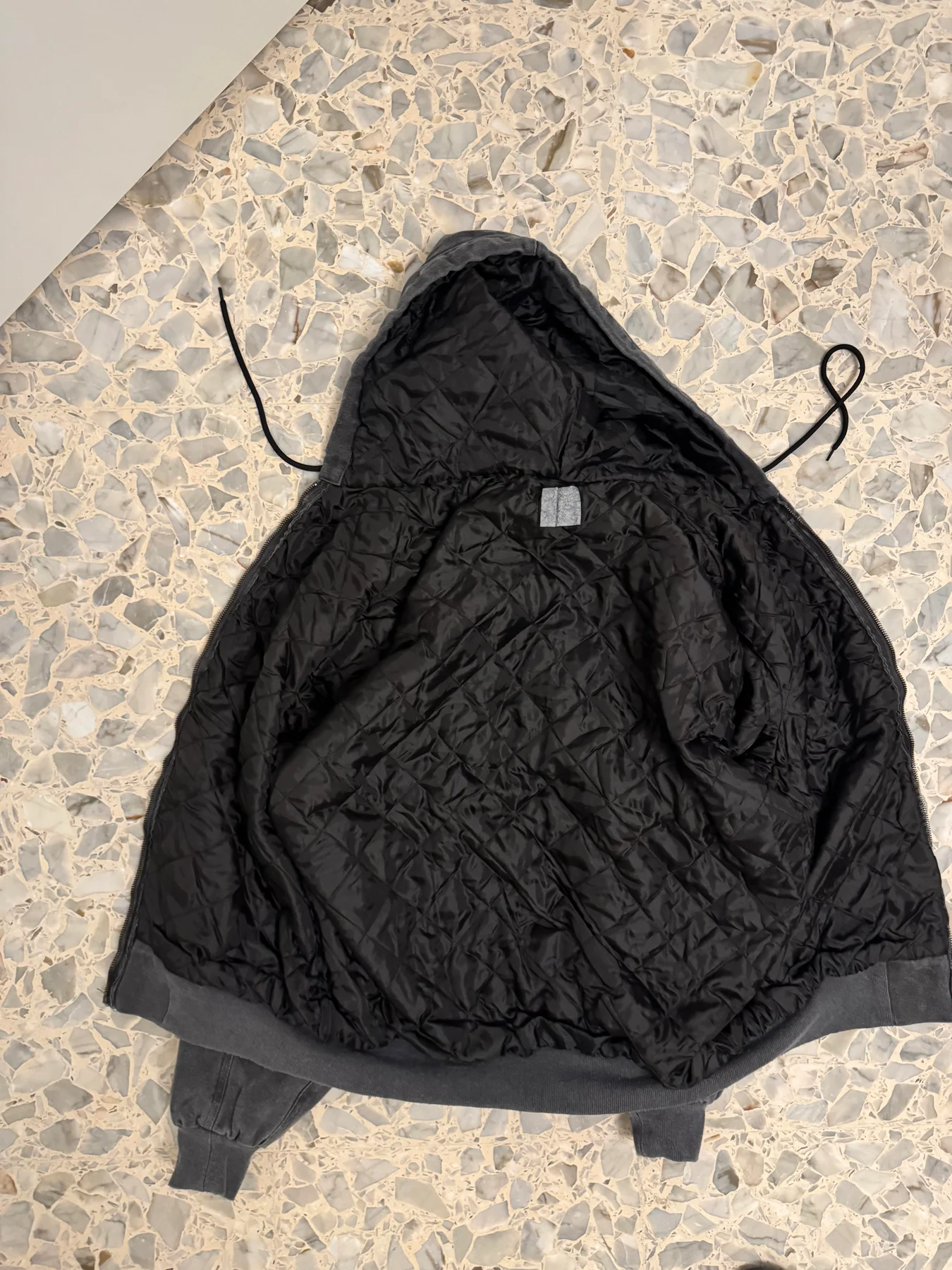 Quilted lining inside the dark hooded jacket.
