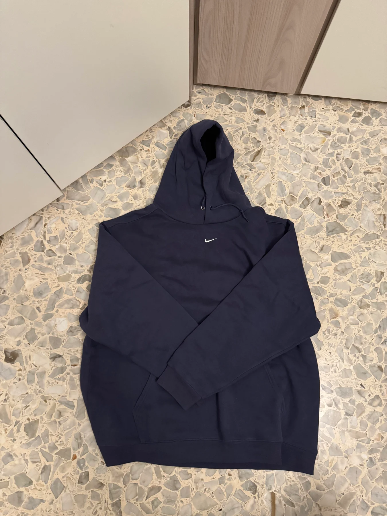 Dark Nike hoodie laid flat.